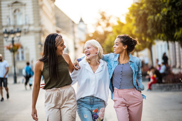 three young women walking together on city street.