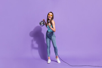 Full size photo of young cheerful smiling excited girl singing in karaoke hold disco ball isolated on violet color background