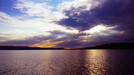 Wall Mural - golden sunset on the lake before a thunderstorm. dramatic sky. reflection of sunlight in water. ripp