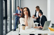 © standret - Woman in front of her colleagues. Group of people in official formal clothes that is indoors in the office