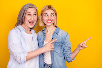 Sticker - Photo portrait of curious mother and daughter showing fingers empty space recommending isolated bright yellow color background