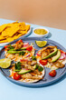Tacos with crispy fish, avocado, guacamole sauce, nachos chips and lime. Mexican cuisine
