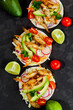Tacos with crispy fish, avocado, guacamole sauce and lime on dark background. Top view. Mexican cuisine