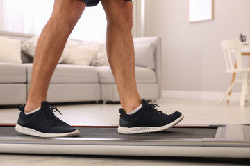 Wall Mural - Man training on walking treadmill at home, closeup