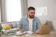 © New Africa - Young man taking notes during online webinar at table indoors