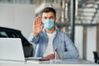 © standret - Uses laptop. Young man in white shirt and blue jacket works indoors