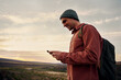 © StratfordProductions - Happy male hiker using smartphone on mountain top