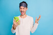 Photo portrait of screaming man holding phone in one hand isolated on vivid blue colored background