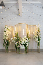 Metal Gold Design With Rectangular Light Bulbs And Fresh Flowers On A White Wall Background