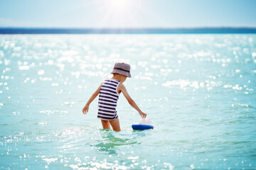 Wall Mural - Cute boy playing with ship toy in the water at the sea.