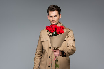 stylish man holding bouquet of red roses isolated on grey