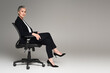 © LIGHTFIELD STUDIOS - Middle aged businesswoman with crossed legs looking at camera on office chair on grey background