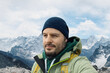 © TeamDF - Man with backpack trekking in mountains. Cold weather, snow on hills. Winter hiking portrait