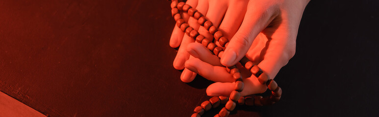 Sticker - cropped view of hands of nun with prayer beads on black surface, banner