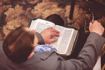 Canvas Print - Top view shot of a man with a book and glasses