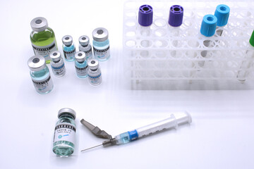 Vaccine vials next to a syringe seen from above 