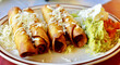 Plate of tasty Mexican flautas with cheese and guacamole