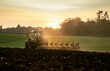 © The Picture Pantry - Ploughing a field at sunset with a tractor and plough, ready for crops on a farm