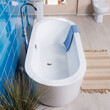 Beautiful front view of elegant white tub next to blue brick wall with a blue towel