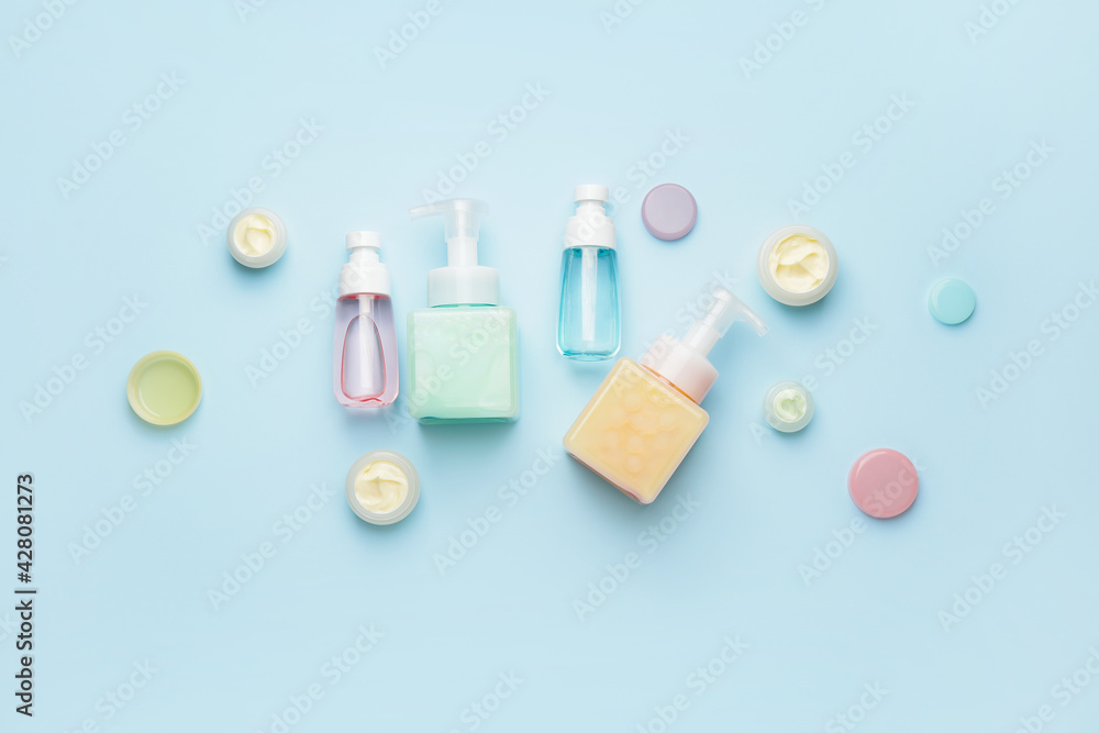 Different bottles of cosmetic products on color background