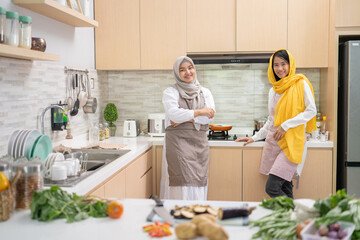 Wall Mural - two attractive young muslim woman preparing iftar dinner together. Ramadan and eid mubarak cooking in the kitchen