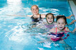 © olenap - Mother with two daughters having fun in indoor swimming-pool. Girl is resting at the water park. Swimming school for small children. Concept friendly family sport summer vacation. Selective focus