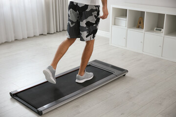 Sporty man training on walking treadmill at home, closeup