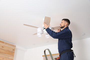 Sticker - Electrician repairing ceiling fan indoors. Space for text