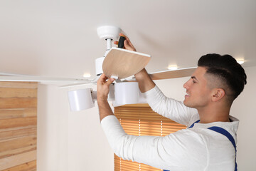 Canvas Print - Electrician with screwdriver repairing ceiling fan indoors