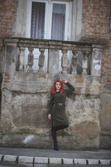 Poster - Attractive young Caucasian female with red hair in a green dress posing in front of an old building