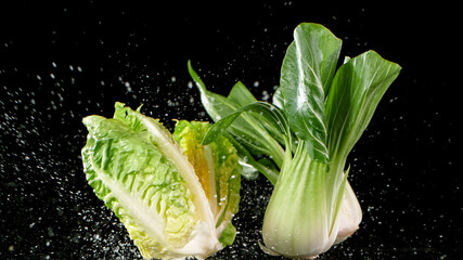 Fresh lettuce falling on black background.