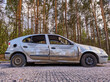 Dumped and damaged car wreck at a car park in a forest