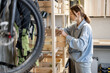 © rh2010 - Young handywoman searching some working tools on a wooden shelves in the workshop. Concept of organization in home workshop or storage