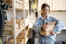 Young Handywoman Searching Some Working Tools On A Wooden Shelves In The Workshop. Concept Of Organization In Home Workshop Or Storage