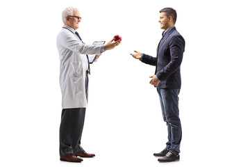 Wall Mural - Full length profile shot of a doctor giving a red apple to a man