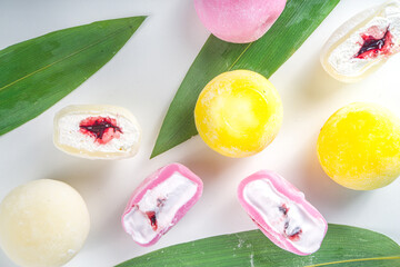 Wall Mural - Traditional Japanese dessert mochi. Colorful mochi ice cream on a white table, whole and cut with berry, fruit filling