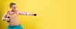 © kalinichenkod - Funny fat man in sportswear with dumbbells in his hands. Overweight man goes in for sports. Yellow background isolate
