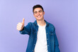 © luismolinero - Teenager caucasian  handsome man isolated on purple background with thumbs up because something good has happened
