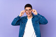 © luismolinero - Teenager caucasian  handsome man isolated on purple background with glasses and surprised