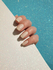 Wall Mural -  female hand beautiful beige manicure on a colored background