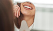 © Ivan - Happy young woman smiling checking out her perfect healthy teeth in the mirror close up, at the dentist office