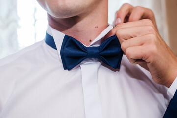 Wall Mural - Blue bow tie in the hands of the groom. Bow tie in the hands of a man