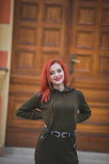 Poster - A red-haired young female in a beautiful winter dress posing in front of a historic building