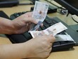 © FranciscoJavier - hands of a woman holding Colombian money on a computer keyboard