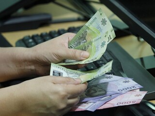 hands of a woman holding Chilean money on a computer keyboard