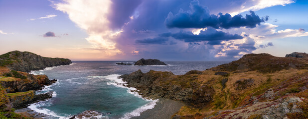 Striking panoramic seascape view on a rocky Atlantic Ocean Coast during a vibrant sunset. Dramatic Sky Art Render. Taken at Crow Head, North Twillingate Island, Newfoundland and Labrador, Canada.