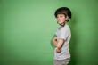 cool brave boy with broken arm and green hand plaster poses with skater helmet in front of green background in the studio