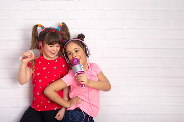 two little girl with a microphone singing together and playing