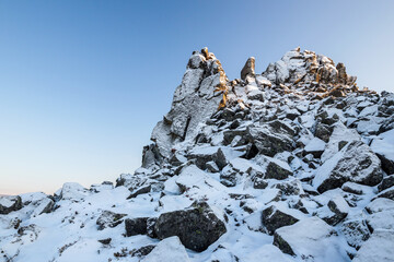 Wall Mural - Winter mountain landscape. View of the snow-capped rocks. Snow on a rocky mountain peak. Travel and mountain hikes. Magadan Region, Russian Far East. The harsh nature of the Magadan region and Siberia