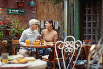 Wall Mural - An older woman and her young female friend having a conversation while they have a drink in the bar. Leisure, bar, friendship, outdoor